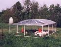 Penâ€™s PVC pipe frame, chicken-wire walls, canvas hoop roof, feeder and water trough inside, and water storge contained atop one corner outside.