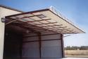 Being fully open, this aluminum buildingâ€™s large door is parallel to and about 16 feet above the concrete entry pad.