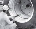 An adult male operating a pneumatic drill with the foot-long impact socket clamped on to a tractor wheel lug nut.