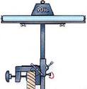 An adult male cuts with table saw a length of 2x4 that is resting on the two rollers of the device, which has been clamped to a workbench.